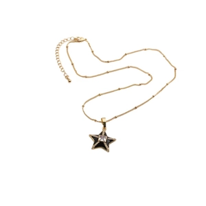 Close-up of golden beaded chain with black star pendant and sparkling center zircon