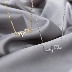 Gold and silver heart rhythm necklaces with sparkling crystal pendants on grey silk