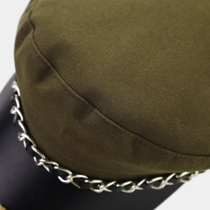 Detail of olive green fabric newsboy cap with black leather brim and silver chain strap