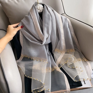 Detail of grey silk mesh scarf with elegant gold beads and metallic gold borders