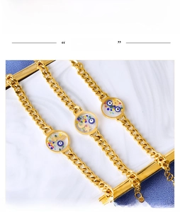 Macro shot of Cuban chain bracelets with evil eye and star charms on marble
