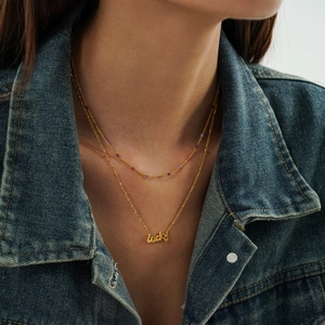 Close-up of double-layered gold stainless steel necklace with Lucky pendant and beads