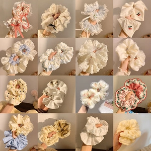 Macro view of 16 assorted floral lace and chiffon hair scrunchies with pleated textures