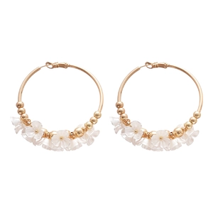 Gold hoop earrings with elegant white acrylic flowers and pearls on white background