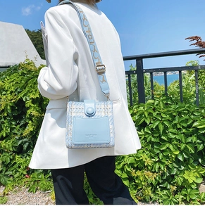 Detail of light blue tweed bucket bag with a wide geometric shoulder strap for women