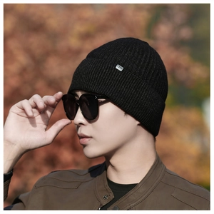 Close-up of black ribbed knit beanie with FERS square logo on male model outdoors