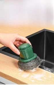 Close-up of kitchen cleaning brush with green handle and replaceable stainless steel scrubber