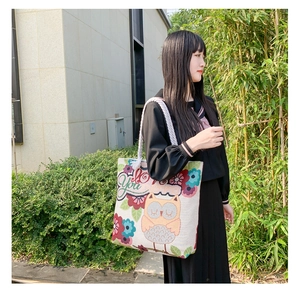 Outdoor shot of cream canvas tote bag with owl floral pattern and rope handles