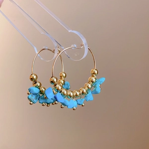 Detailed macro view of bohemian gold hoop earrings with irregular turquoise stone beads
