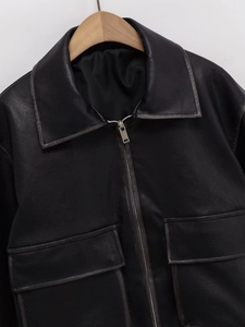Close-up of a black leather jacket featuring a lapel collar and metal zipper details