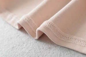 Detailed macro view of pink knitted fabric texture and premium double-stitch overlock seams