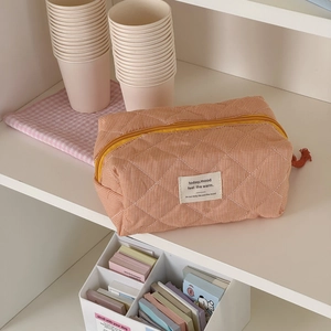 Detail der orangefarbenen gesteppten Kosmetiktasche mit weicher Textur und gelbem Reißverschluss