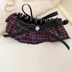 Detailed view of plaid bow hair clip with sparkling rhinestone flower and ribbon texture