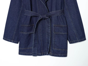 Détail d'une robe en jean bleue avec ceinture à la taille et grandes poches avant