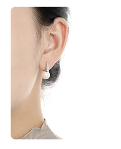 Macro detail of a pearl stud earring with silver spiral base worn on a model's ear