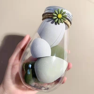 Detail of colorful makeup sponges in a clear jar decorated with a daisy and twine