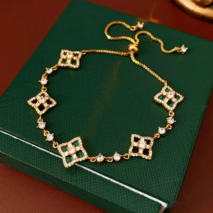 Détail du bracelet doré réglable avec pierre verte et motif de fleur évidée
