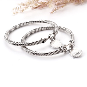 Macro detail of silver stainless steel cable bracelets with St. Benedict coin pendants