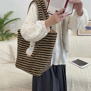Detail of plush tote bag with black and brown stripes and a cute white dog embroidery