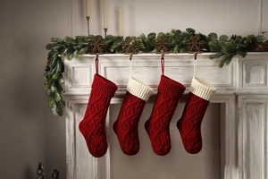 Detail of red and white knitted Christmas stockings hanging on a festive fireplace mantel