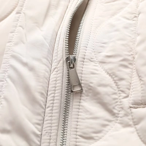 Detailed macro view of high-quality silver metal zipper on quilted cream fabric