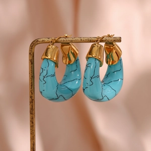 Detail of C-shaped turquoise acrylic earrings with marble texture on golden hooks