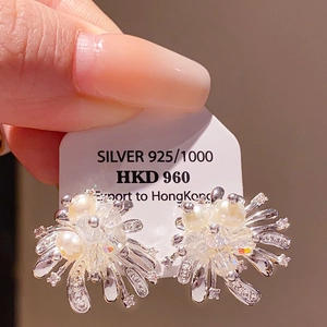 Macro shot of silver 925 starburst earrings with pearls and crystals on a white display card