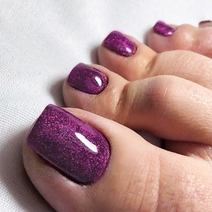 Close-up of glitter purple press-on toenails showing glossy texture and shimmer effect