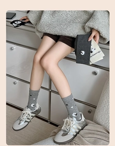 Détail de chaussettes grises avec motifs de moutons mignons et cœurs en tricot doux