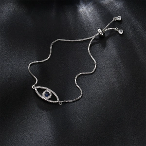 Silver evil eye bracelet with blue zircons and adjustable sliding clasp on black texture