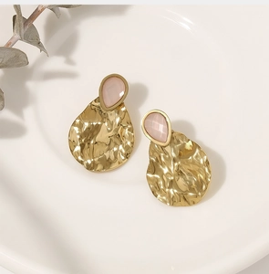 Macro view of gold hammered earrings featuring pink aventurine natural stone insets
