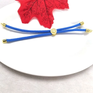 Macro detail of adjustable blue woven rope bracelet with 18k gold plated tree bead