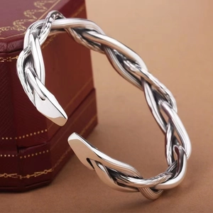 Retro Thai silver twist weave open bangle with polished metallic finish on brown background