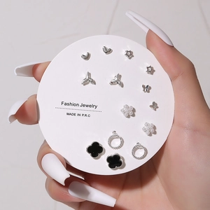 Macro detail of silver and black stud earring set with clover and pearl motifs