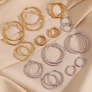 Macro detail of multi-size gold and silver hoop earrings with inlaid colorful crystals