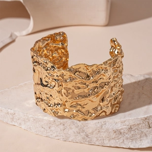 Detailed view of the irregular molten texture on a wide gold-plated open cuff bracelet