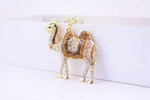 Close-up of golden camel keychain featuring sparkling amber crystals and enamel detail