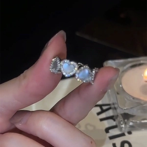 Geometrische hartvormige zilveren ring met opalen en fonkelende zirkoon op een vinger