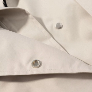Macro detail of beige twill trench coat collar with silver metal snap button closures