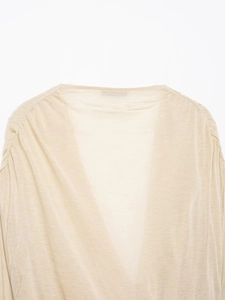 Close-up of beige V-neck top showing shoulder pleated details and soft knit fabric texture