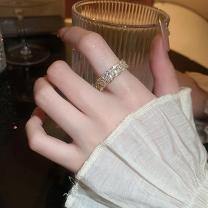 Detail view of a gold-plated ring with rectangular zircon stones worn on a finger