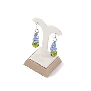 Orecchini con perle verdi floreali e cristalli blu su espositore per gioielli bianco