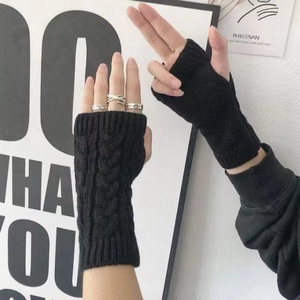 Primer plano de guantes de punto trenzado sin dedos negros que muestran la textura fina