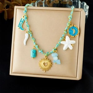 Detail of gold pendant necklace with light blue woven rope and colorful charms