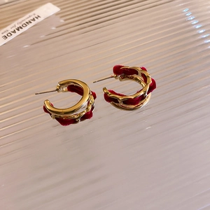 Detailed macro view of gold-tone C-shape earrings with red velvet chain weave