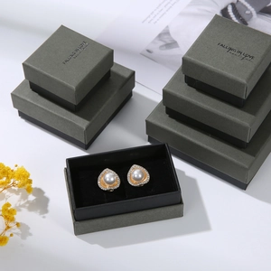 Detail of matte gray jewelry gift boxes featuring heart pearl earrings and elegant lettering