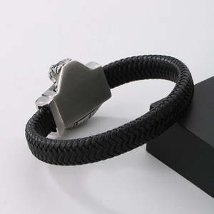 Macro detail of men's black braided leather bracelet with brushed steel clasp