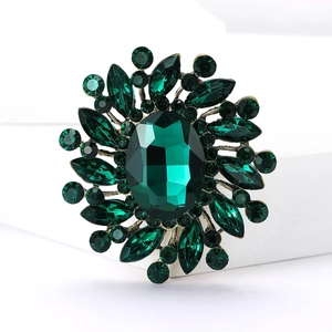 Macro shot of radial sunflower brooch with green crystals on vintage black gold base