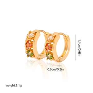 Detail view of gold earrings with square zircon gems in white, orange and green colors