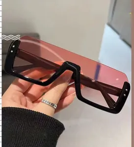 Detail van een vierkante oversized zonnebril met zwart montuur en roze gradiëntglazen